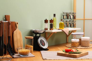 Kitchen scale, products and cooking utensils on wooden table