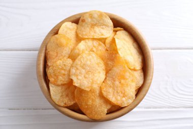 Beyaz ahşap masada, tabakta patates cipsi.