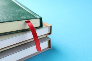 Kırmızı kurdele yer imi ve açık mavi arka planda renkli kitap, yakın plan. Metin için boşluk