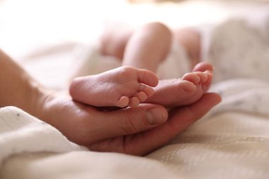 Anne, küçük bebeği evde, yatağında, yakın plan.