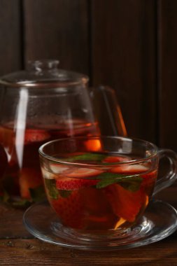 Çilekli Aromatik meyve çayı ve ahşap masada nane şekeri, yakın plan.