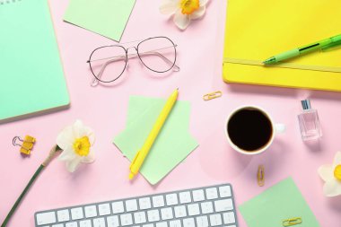 Pembe arka planda kırtasiye ve çiçeklerle düz kompozisyon