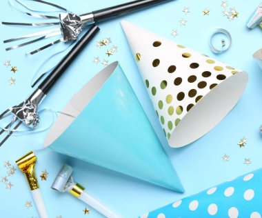 Açık mavi arka planda parti şapkaları ve konfetileri ile düz konum