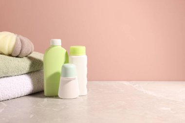 Açık kahverengi duvarın yanındaki gri masada farklı banyo ürünleri. Metin için boşluk