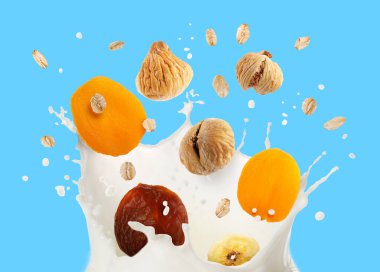 Süt sıçraması, yulaf ezmesi ve açık mavi arka planda kuru meyveler.