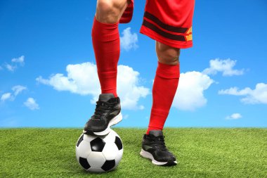 Mavi gökyüzünün altında futbol topu olan futbolcu, yakın plan