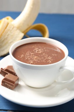 Lezzetli çikolatalı süt, parçalar ve muz mavi masada, yakın plan.