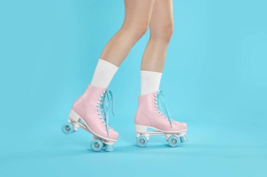 Açık mavi arka planda patenli kadın, yakın plan.
