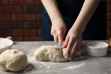 Açık gri masada hamur kesen kadın, yakın plan.
