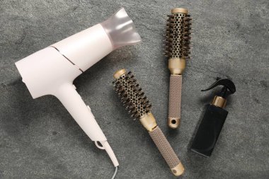 Gri dokulu arka planda farklı saç şekillendirme araçları, düz yatış