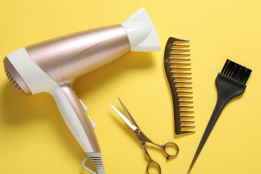 Sarı arka planda farklı saç şekillendirme araçları, düz yatış