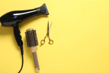 Sarı arka planda farklı saç şekillendirme araçları, düz yatış. Metin için boşluk