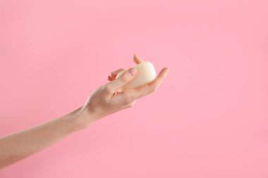 Açık pembe arka planda sabun çubuğu olan kadın, yakın plan. Metin için boşluk