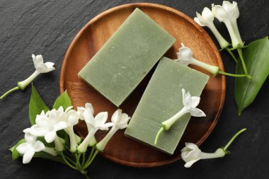 Siyah masanın üzerinde sabun ve yasemin çiçekleri yatıyordu.