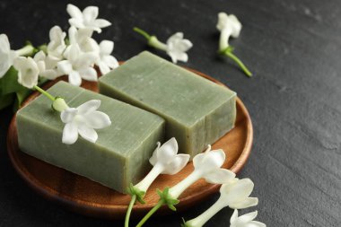 Siyah masada sabun ve yasemin çiçekleri, yakın plan. Metin için boşluk