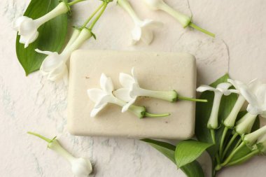 Bir kalıp sabun ve yasemin çiçekleri ışık masasında, düz yatıyordu.