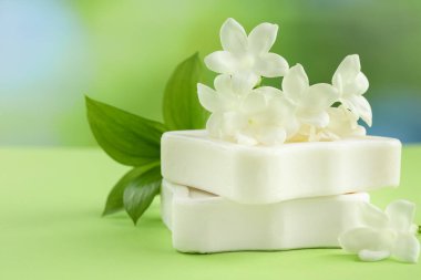 Açık yeşil masada sabun ve yasemin çiçekleri bulanık arka planda, yakın planda