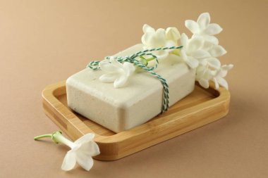 Açık kahverengi arka planda sabun ve yasemin çiçekleri, yakın plan.