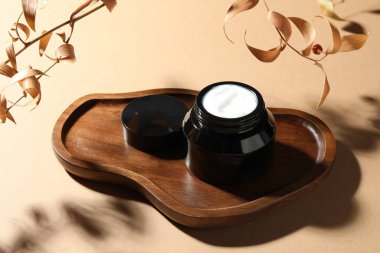 Bej arka planda bir kavanoz vücut kremi ve kuru dallar, yakın plan.