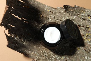 Bej arka planda vücut kremi ve ağaç kabuğu kavanozu, üst görünüm