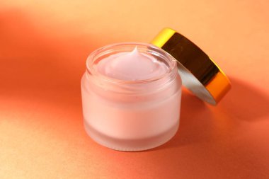 Turuncu arka planda bir kavanoz nemlendirici vücut kremi, yakın plan.