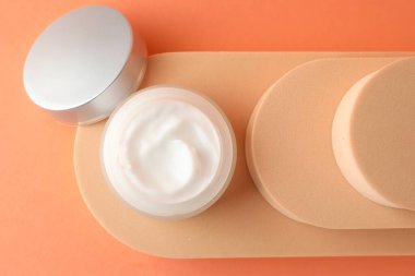 Turuncu arka planda kavanozda nemlendirici vücut kremi sunumu.