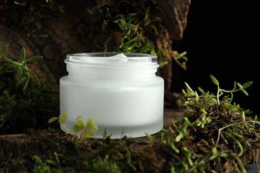 Ağaç kabuğunda bitkilerle birlikte nemlendirici vücut kremi, yakın plan.