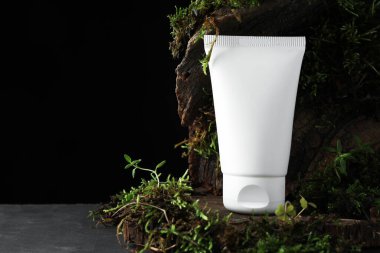 Nemlendirici vücut kremi, ağaç kabuğu ve bitkiler gri masada, yakın plan. Metin için boşluk