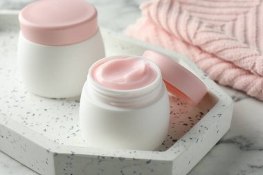 Beyaz mermer masanın üzerinde bir kavanoz nemlendirici vücut kremi, yakın plan.