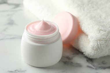 Beyaz mermer masanın üzerinde bir kavanoz nemlendirici vücut kremi, yakın plan.