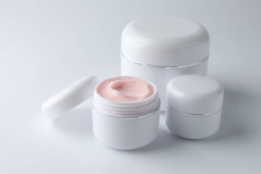 Beyaz arka planda nemlendirici vücut kremi kavanozları, yakın plan.