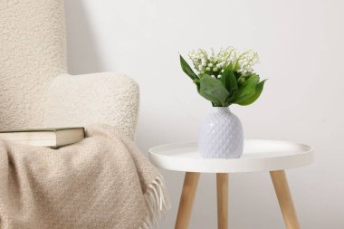 Vadinin güzel zambaklarından oluşan bir buket vazo, kahve masasının üstünde, içerideki koltuğun yanında.