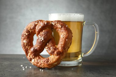 Lezzetli kraker ve bir bardak bira koyu desenli masada gri arka planda, yakın plan