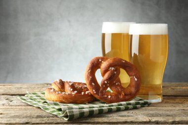 Lezzetli krakerler ve bira bardakları ahşap masada gri arka planda, yakın plan