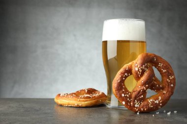 Lezzetli krakerler ve koyu dokulu masada bir bardak bira. Gri arka planda, yakın plan. Metin için boşluk