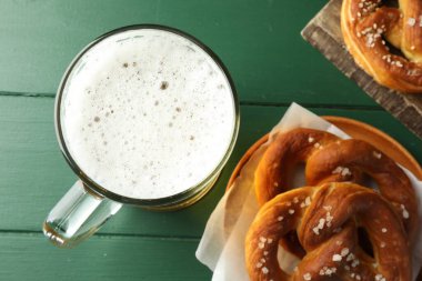 Lezzetli krakerler ve yeşil ahşap masada bir bardak bira.