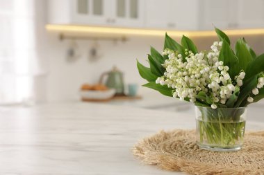 Mutfaktaki beyaz mermer masanın üzerinde, vadideki güzel zambak demeti, yakın plan. Metin için boşluk