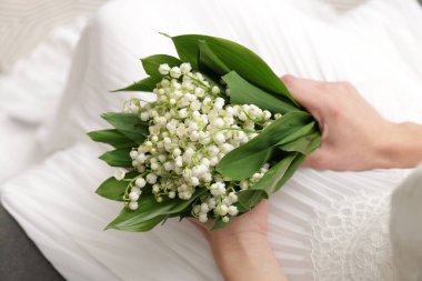 Gelin, vadideki güzel zambaklardan bir buket, kapalı bir kanepede, yakın plan.