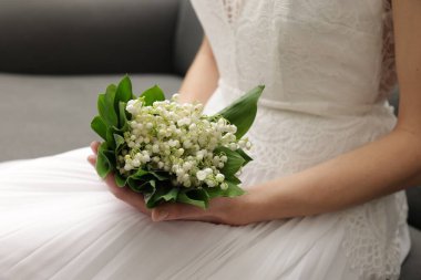 Gelin, vadideki güzel zambaklardan bir buket, kapalı bir kanepede, yakın plan.