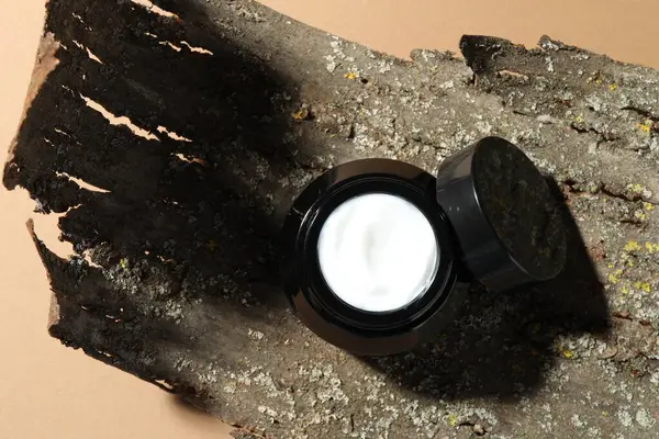 Bej arka planda vücut kremi ve ağaç kabuğu kavanozu, üst görünüm