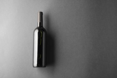 Gri arka planda bir şişe şarap, üst manzara. Metin için boşluk