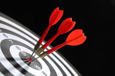 Hedef alınıyor. Siyah arkaplanda okları olan dart tahtası, yakın plan