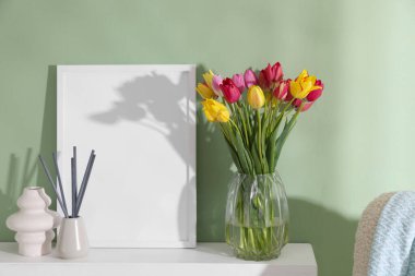 Renkli duvarın yanındaki masada bir buket güzel lale ve dekor.