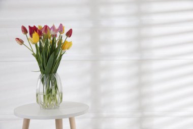 Beyaz duvarın yanındaki masada bir buket güzel lale. Metin için boşluk