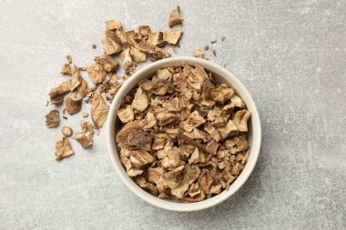 Kase içindeki kuru hindiba kökleri gri desenli masa, üst manzara.