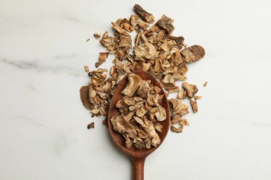 Beyaz masadaki kaşıkta kuru hindiba kökleri.