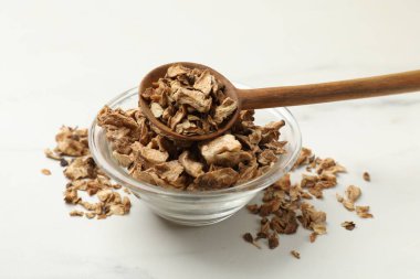 Kuru hindiba kökleri kasede ve kaşıklar beyaz masada, yakın plan.