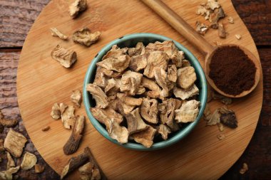 Kuru hindiba kökleri kasede ve kaşıkta, tahta masanın üstünde toz var.