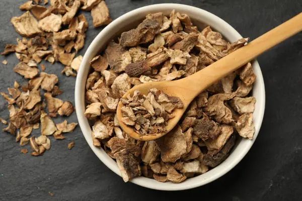 Kuru hindiba kökleri kasede ve kaşıkla koyu dokulu masa, üst görüş.