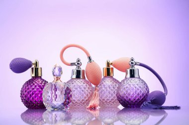 Ayna yüzeyinde soluk menekşe eğimli arka planda parfüm şişeleri